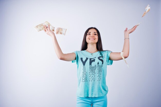 Retrato de una chica atractiva con camiseta azul o turquesa y pantalones tirando mucho dinero