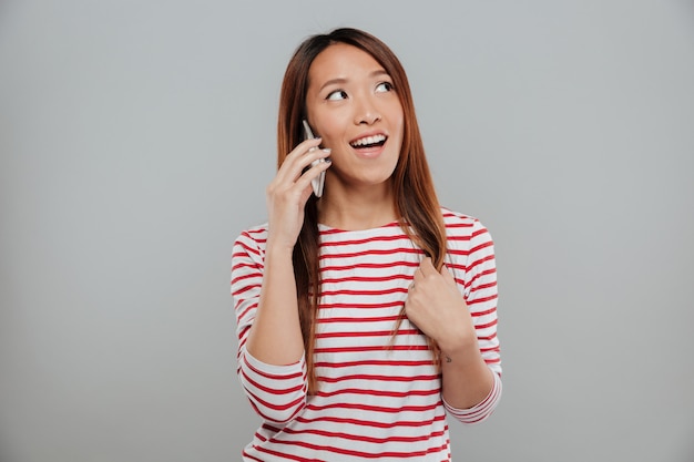 Retrato de una chica bonita asiática hablando por teléfono móvil