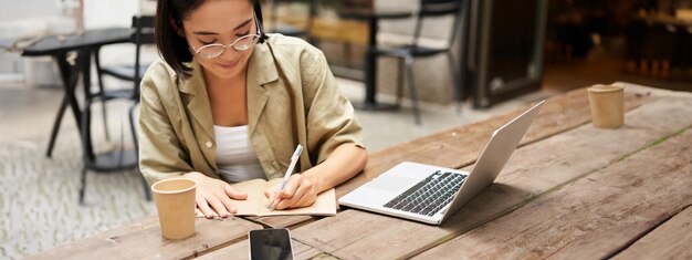 Retrato de una chica concentrada haciendo los deberes asistiendo a un curso en línea tomando notas mientras trabaja