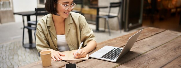 Retrato de una chica concentrada haciendo los deberes asistiendo a un curso en línea tomando notas mientras trabaja