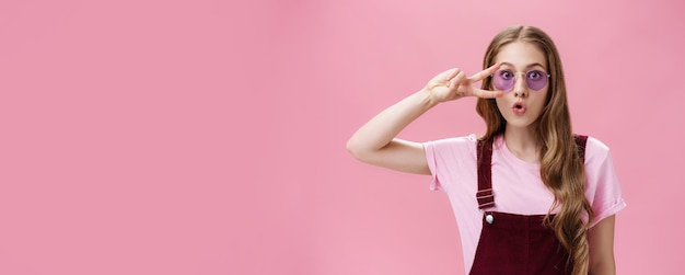 Foto gratuita retrato de una chica elegante y enérgica con una cicatriz en la mano que muestra el signo de la paz sobre el ojo usando sungla fresco