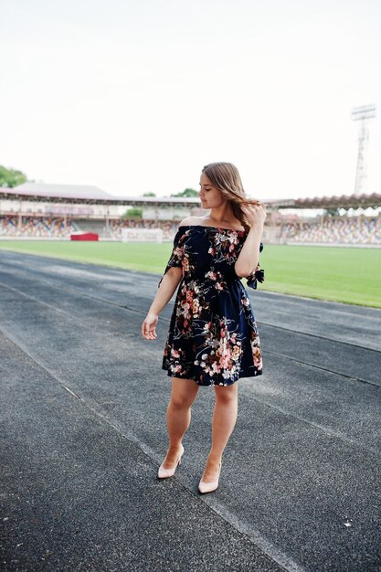 Retrato de una chica fabulosa vestida y tacones altos en la pista del estadio