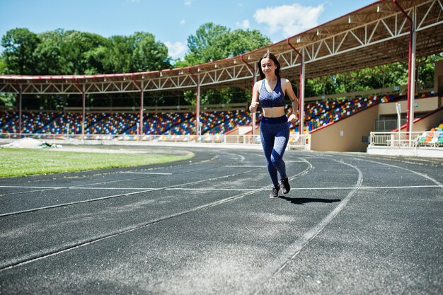 Retrato de una chica fuerte en ropa deportiva corriendo en el estadio