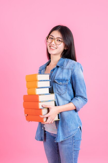 Retrato chica guapa adolescente sosteniendo la pila de libros y smiley en rosa, concepto de educación teenge