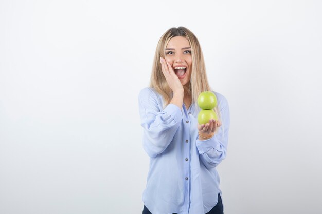 retrato de una chica guapa modelo de pie y sosteniendo manzanas frescas.