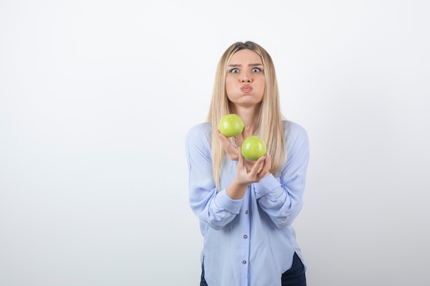 Foto gratuita retrato de una chica guapa modelo de pie y sosteniendo manzanas frescas.