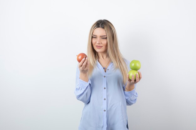 retrato de una chica guapa modelo de pie y sosteniendo manzanas frescas.