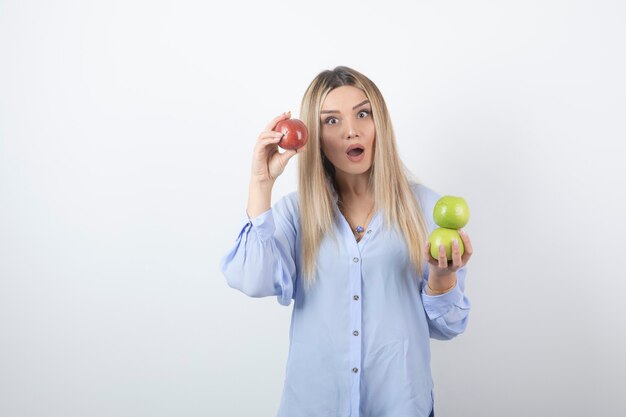 retrato de una chica guapa modelo de pie y sosteniendo manzanas frescas.