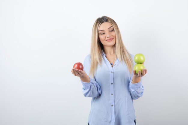 retrato de una chica guapa modelo de pie y sosteniendo manzanas frescas.