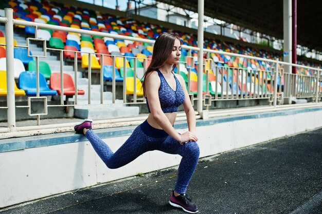 Retrato de una chica hermosa haciendo sentadillas en el estadio