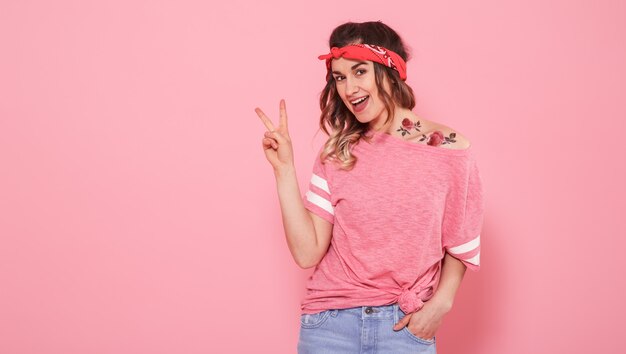 Retrato de una chica hipster con tatuaje, aislado en pared rosa