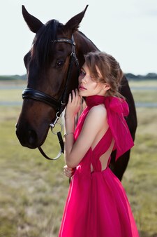 retrato de una chica joven encantadora en un vestido con un caballo