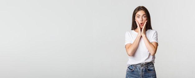 Retrato de una chica morena sorprendida y divertida que parece maravillada jadeando impresionada