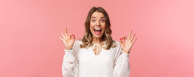 Retrato de una chica rubia alegre, emocionada y optimista, vestida de blanco, bailando y mostrando señales de estar bien con una sonrisa feliz y radiante, emocionada por el ritmo del festival de música, película increíble, producto recomendado