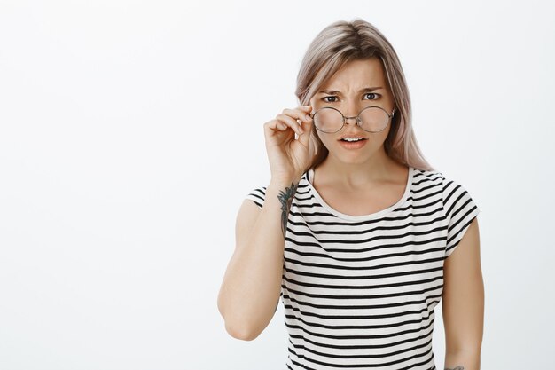 Retrato de chica rubia insegura con gafas posando en el estudio