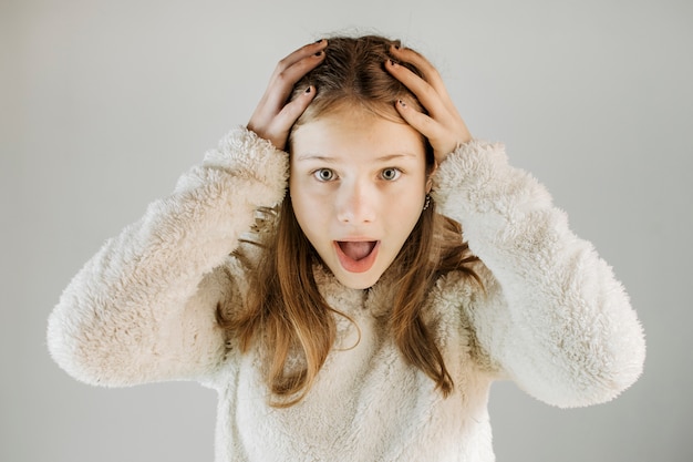 Retrato de una chica sorprendida con la mano en la cabeza