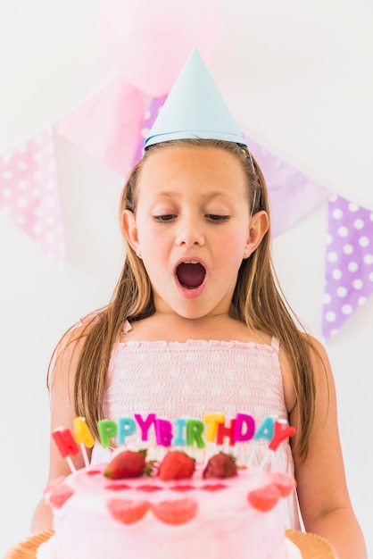 Retrato de una chica sorprendida mirando su hermoso pastel de cumpleaños