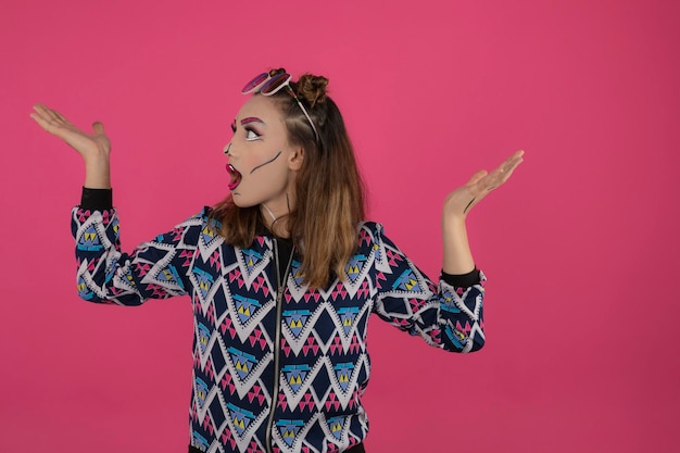 Retrato de una chica sorprendida usando maquillaje creativo y levantando las manos. foto de alta calidad