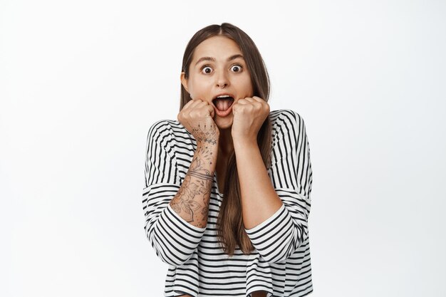 El retrato de una chica se ve sorprendida y emocionada, deja caer la mandíbula y jadea fascinada, mira algo impresionante, fondo blanco