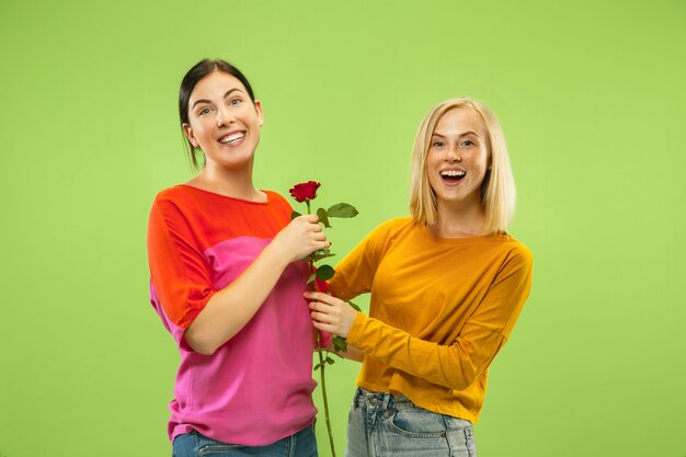 Retrato de chicas muy encantadoras en trajes casuales aislados en la pared verde del estudio