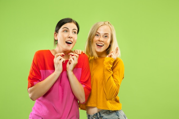 Retrato de chicas muy encantadoras en trajes casuales aislados en la pared verde del estudio