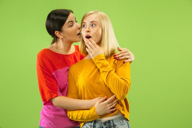 Retrato de chicas muy encantadoras en trajes casuales en estudio verde