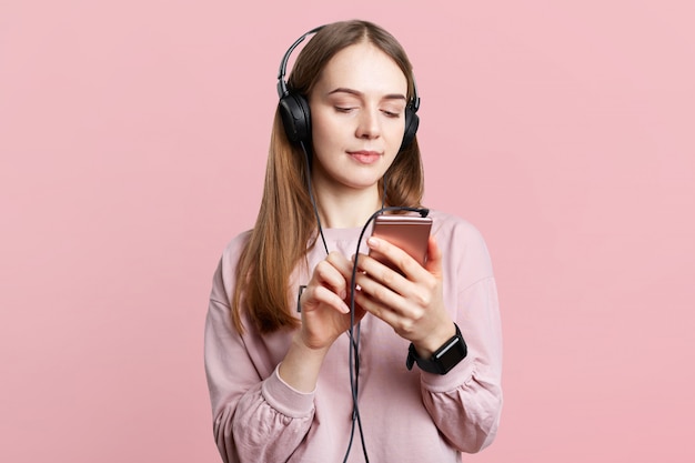 El retrato de la cintura de la bella mujer morena usa auriculares, revisa la canción de la lista de reproducción