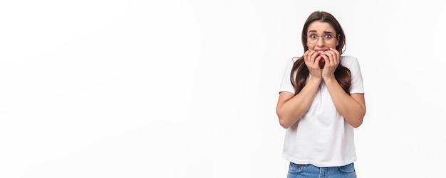 Foto gratuita el retrato en la cintura de una joven morena asustada en exámenes de pánico está cerca de sentirse asustado mordiendo el dedo