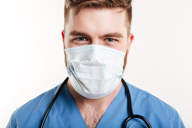 Retrato de un cirujano masculino concentrado con estetoscopio y máscara