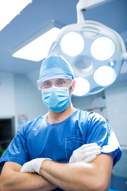 Retrato del cirujano de pie con los brazos cruzados en la sala de operación