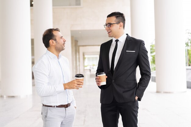 Retrato de colegas hombres de negocios tomando café y hablando