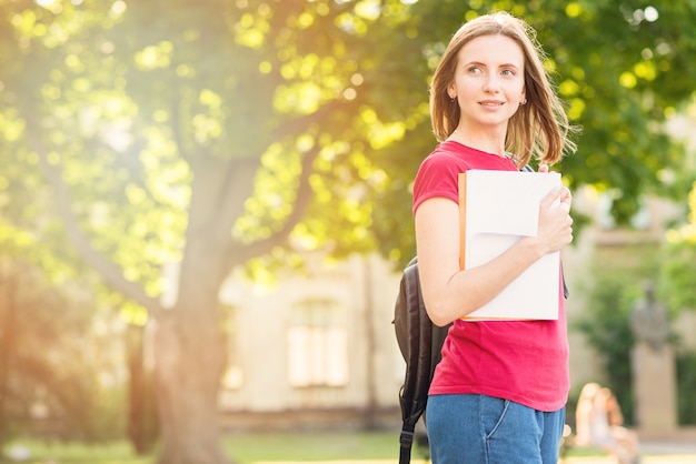 Foto gratuita retrato de colegiada con libros en el parque