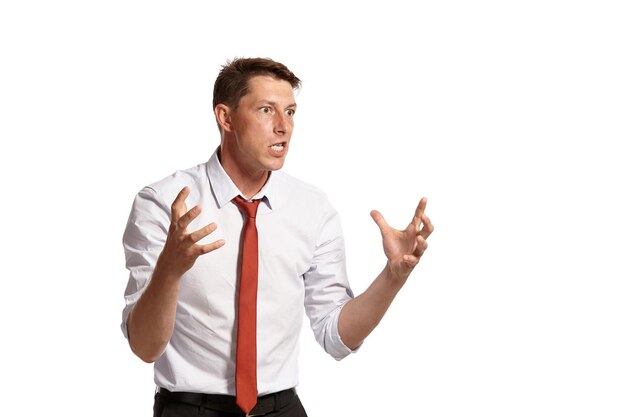 Retrato de un compañero moreno adulto con ojos marrones, vestido con una camisa blanca y una corbata roja. Se ve muy enojado mientras posa en un estudio aislado sobre un fondo blanco. Concepto de gesticulación