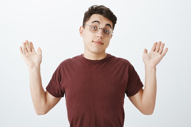 Retrato de compañero de trabajo masculino europeo inconsciente descuidado en gafas redondas y camiseta