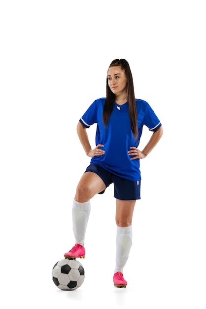 Retrato completo de una joven jugadora de fútbol con uniforme posando con una pelota aislada sobre un fondo blanco de estudio
