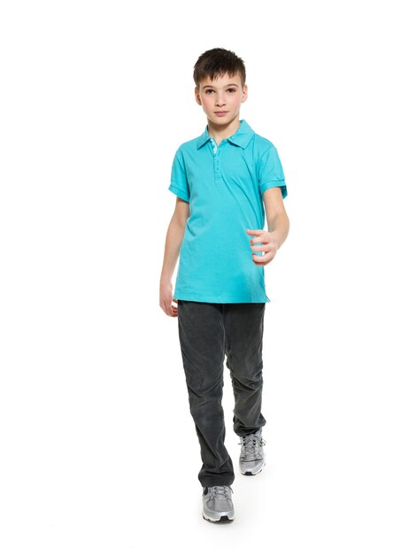 Retrato completo del muchacho adolescente que camina en casuals de la camiseta azul aislado en blanco.