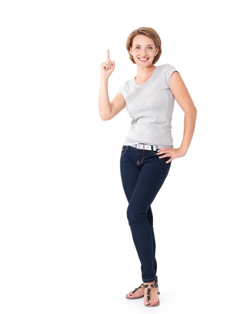 Retrato completo de mujer adulta feliz apuntando hacia arriba con su dedo en blanco