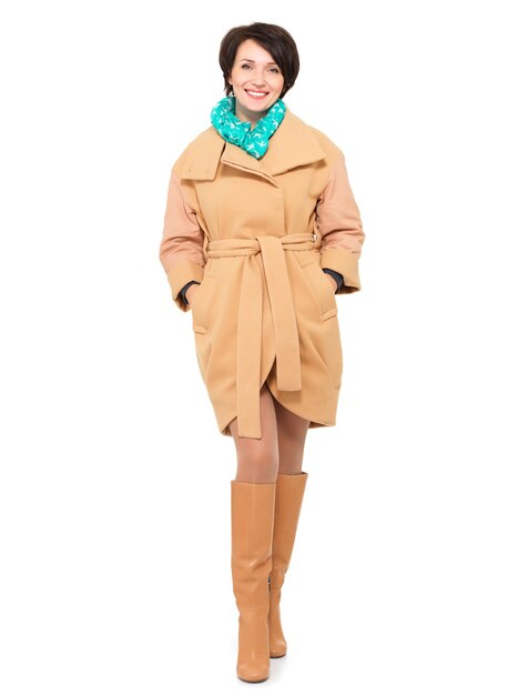 Retrato completo de mujer feliz en abrigo beige de otoño y bota de cuero con pañuelo verde de pie aislado en blanco