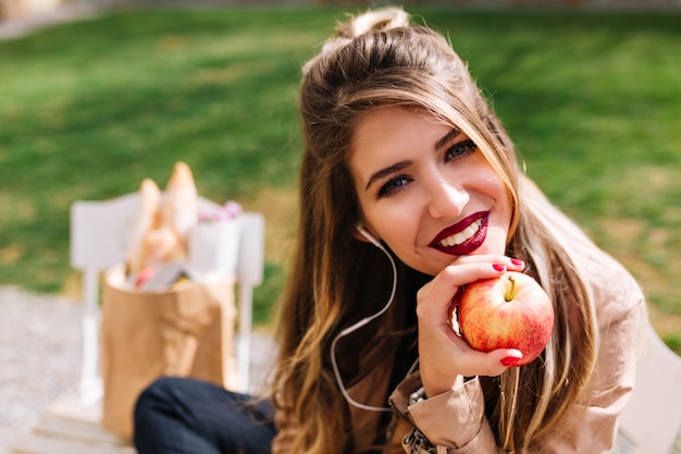 Foto gratuita retrato completo de una niña encantadora apoyó la cara con la mano y mira con interés después de comprar comida