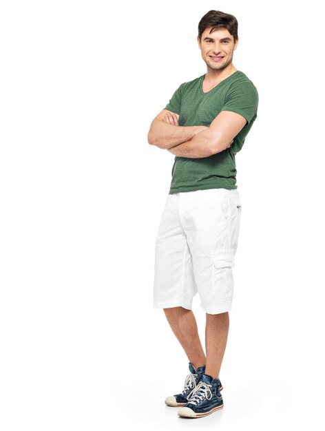 Retrato completo de sonriente feliz guapo en pantalones cortos blancos y camiseta verde aislado en blanco