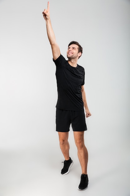 Retrato completo de un sonriente joven deportista de pie