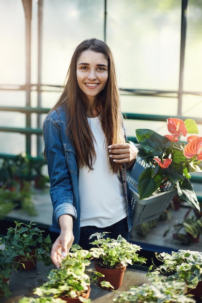 Retrato de una compradora en una tienda de invernaderos que elige qué flor o planta comprar