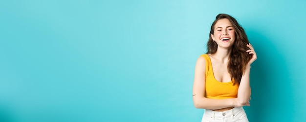 Retrato de concepto de verano y estilo de vida de mujer atractiva riendo y jugando con su cabello suplente