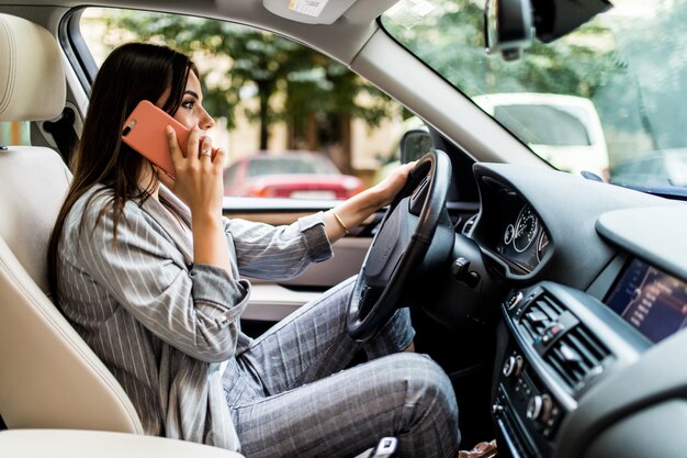 Retrato de conductor imprudente hablando con su teléfono móvil mientras conduce el coche.