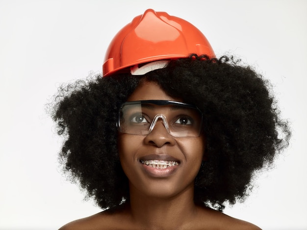Retrato de confiada trabajadora en casco naranja