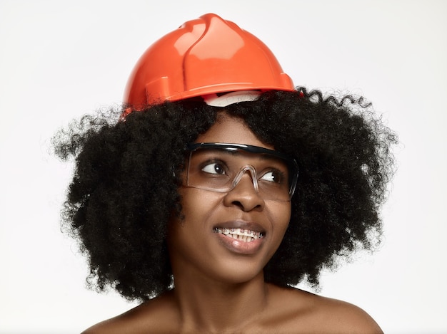 Retrato de confiada trabajadora en casco naranja