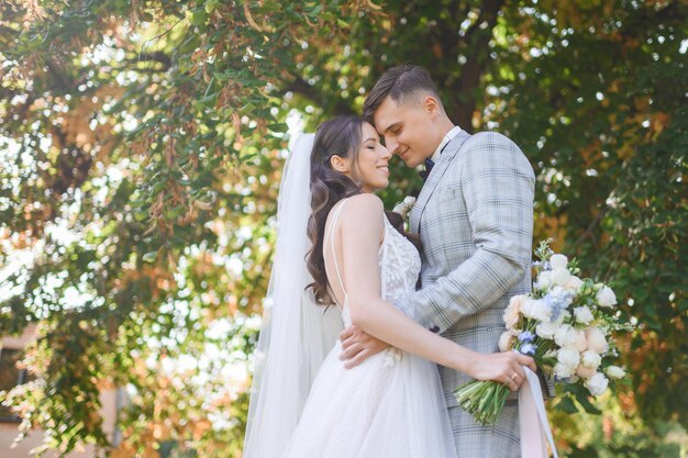 Retrato de cosecha de hermosas novias amorosas pareja hombre en traje elegante con chica en vestido de novia abrazándose tocándose el uno al otro celebrando el día de la boda disfrutando de un momento feliz