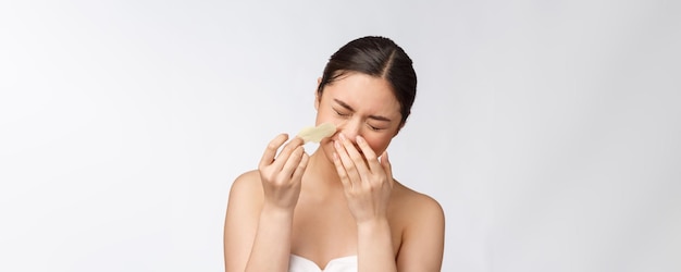 Retrato de cosmetología de hermosa modelo asiática femenina con máscara en la nariz Primer plano de mujer joven sana con piel suave pura y maquillaje natural fresco