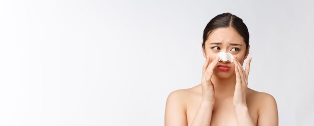 Retrato de cosmetología de hermosa modelo asiática femenina con máscara en la nariz Primer plano de mujer joven sana con piel suave pura y maquillaje natural fresco