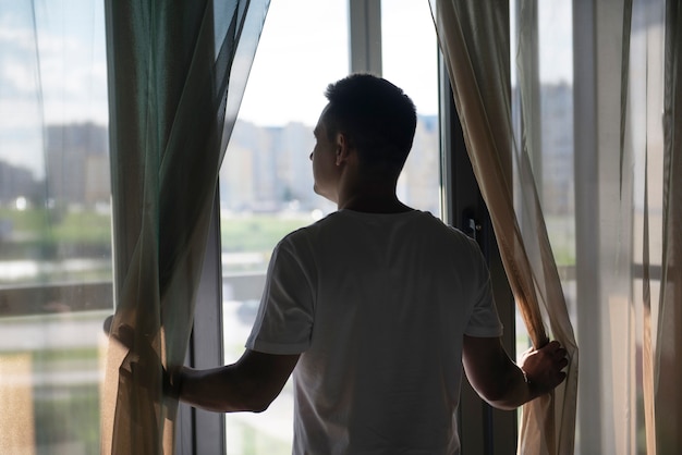 Foto gratuita retrato creativo del hombre con cortinas y sombras desde la ventana.